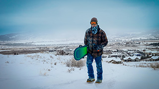 snowboarder standing in the snow holding a board